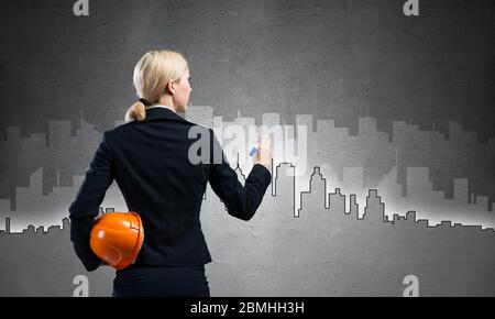 Businesswoman draws silhouette of business center Stock Photo