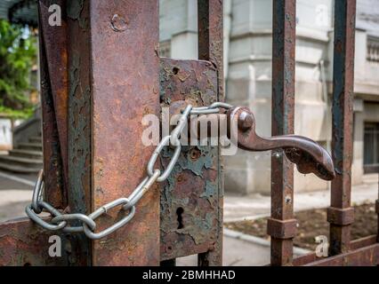 Rusted old gate/door locked with a chain. Detail of an old rusty latch Stock Photo
