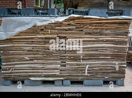 Stacked Carboard Boxes ready for recycling on black plastic pallets. Stock Photo