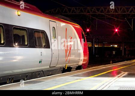 Virgin trains Alstom Pendolino train at crewe railway station on the west coast mainline  with red railway danger signals