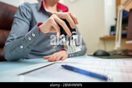 little girl puts a stamp on documents Stock Photo