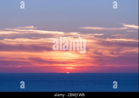 Vibrant sunset over the ocean on a partly cloudy day in summer, Normandy (France) Stock Photo