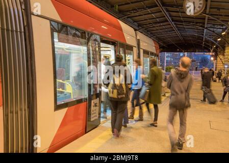 Commuters (blurred) boarding a light rail tram at Central Station during the evening commute in Sydney, Australia Stock Photo