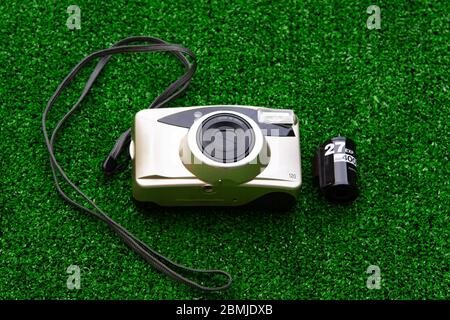 Old film camera with 35mm film cartridge isolated on green grass background Stock Photo