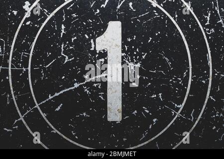 Number one painted on a metal surface. black iron plate with digit 1. scratched paint on steel. rough texture. industrial background Stock Photo