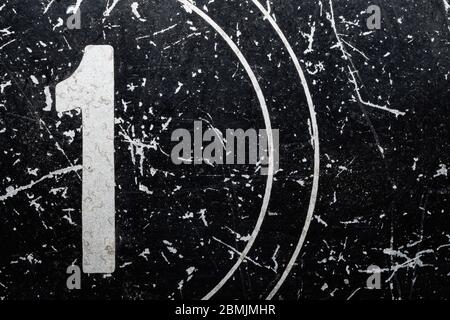 Number one painted on a metal surface. black iron plate with digit 1. scratched paint on steel. rough texture. industrial background Stock Photo