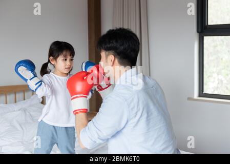 Young Asian dad is playing on bed with daughter Stock Photo