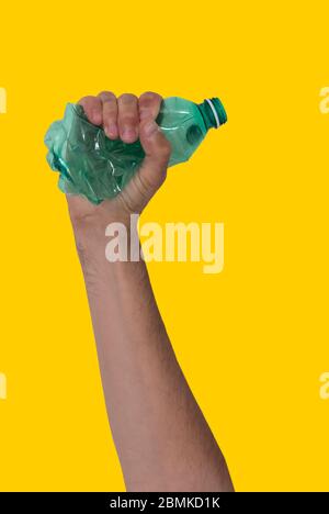 Concept of stop plastic pollution, global warming, recycling plastic, plastic free. Man's hand tightly squeezes an empty green plastic bottle Stock Photo