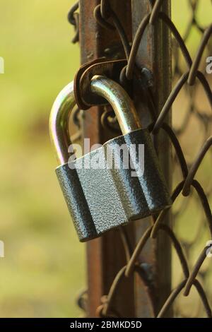 Gray iron shiny padlock hanging on an iron door in the street. Stock Photo