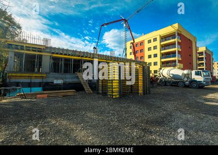 Construction site with cranes, mixer truck and pump truck. New building construction site, near modern luxury apartments. Unfinished construction conc Stock Photo