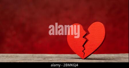 Broken heart. Crack in the red heart, Breaking the relationship. Red background Stock Photo