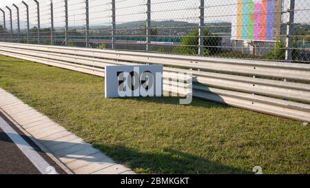 Warning sign or road sign for the maximum speed limit next to an empty road on a sunny summer day. Speed sign on a racetrack. Stock Photo