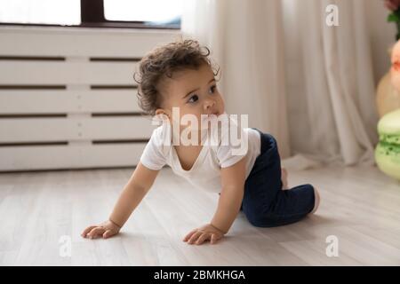 Little biracial baby creep on fours at home Stock Photo