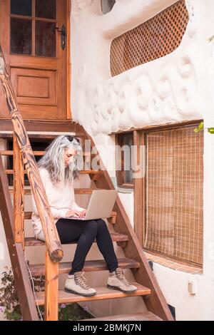 Alternative modern adult people in smart working activity outdoor at home in the garden - concept of modern technology working everywhere -  connected Stock Photo