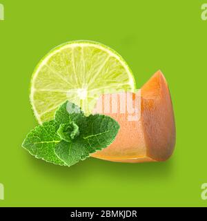 Isolated mix fruits. Lime and melon slices with fresh leaves of mint on colored background with clipping path as package design element and advertisin Stock Photo