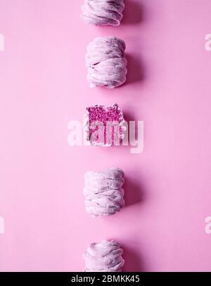 Line of Violet sweet homemade Zephyr or Marshmallow from black currant on pink bright background. One zephyr is cut. Top view Stock Photo