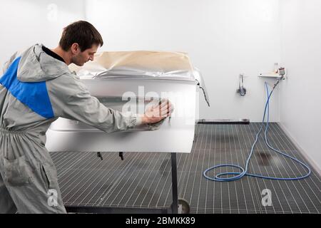Auto mechanic preparing the car for paint job in painting booth in auto repair shop Stock Photo