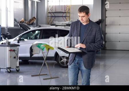 Manager working in auto repair shop with a car on background Stock Photo