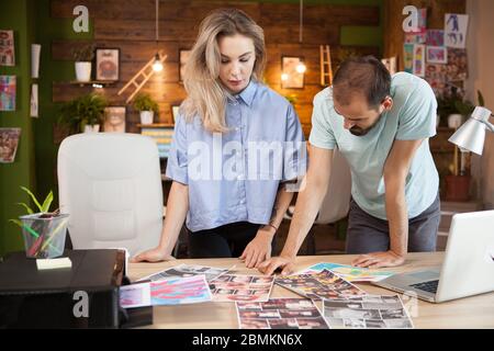 Focused female tailor and fashion designer sharing ideas in creative office. Stock Photo