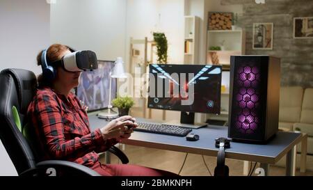 Gamer girl losing video game tournament while playing with VR headset late at night in her room Stock Photo