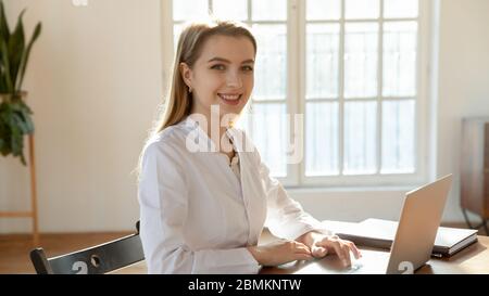 Portrait of smiling female GP working on laptop Stock Photo