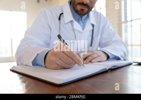 Close up of male doctor writing in medical journal Stock Photo