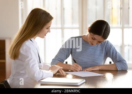 Female patient sign paper contract at meeting with doctor Stock Photo
