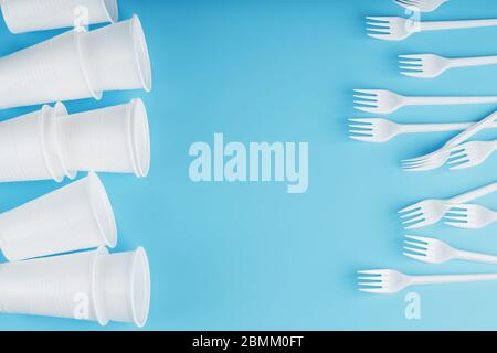Plastic tableware on a blue background. Disposable forks and glasses with free space. The view from the top Stock Photo