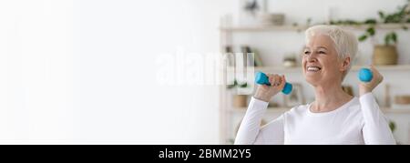 Active Retirement. Sporty senior woman exercising with dumbbells at home