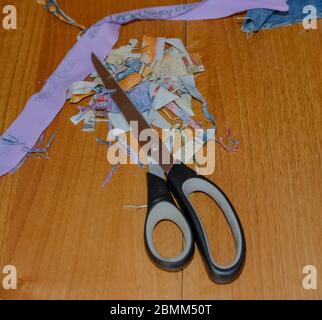 31 Crafting at home. Top down view of crafting scissors and fabric on a wooden table during a home sewing project Stock Photo