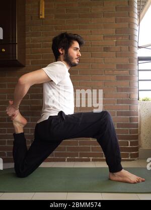 Young handsome caucasian man practicing yoga, stretching. Exercise at home concept. Stock Photo