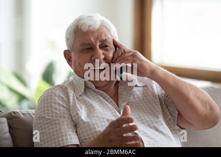 Happy senior man laugh talking on cellphone at home Stock Photo