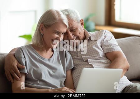 Happy senior couple relax at home using laptop Stock Photo