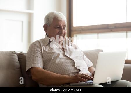 Happy senior man using laptop browsing internet Stock Photo
