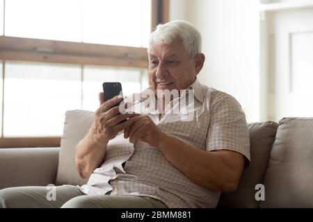 Mature 80s man using modern cell texting Stock Photo