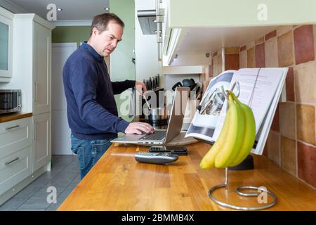 Distressed man under pressure working at home in a kitchen during the Covid-19 Coronavirus Pandemic Quarantine lockdown Stock Photo