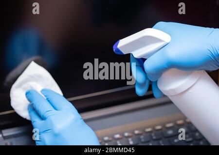 Coronavirus COVID-19 sanitize cleaning disinfection of work desk.Office sanitizing wipe wiping laptop with disinfecting wipes. Stock Photo