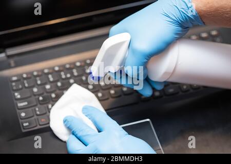 Coronavirus COVID-19 sanitize cleaning disinfection of work desk.Office sanitizing wipe wiping laptop with disinfecting wipes. Stock Photo