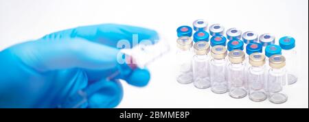 Scientist hand in blue gloves holding coronavirus, covid-19 vaccine disease, preparing for human clinical trials vaccination shot. Medicine and drug c Stock Photo