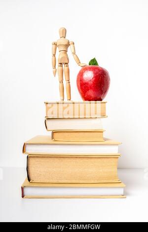 Stuck of books with red apple and wooden mannequin, isolated on white background, vertical composition Stock Photo