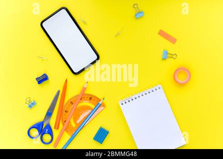 Colored different school supplies on soft yellow paper background. Notebook, pens, pencils and other tools. Back to school background. Mock up. Stock Photo