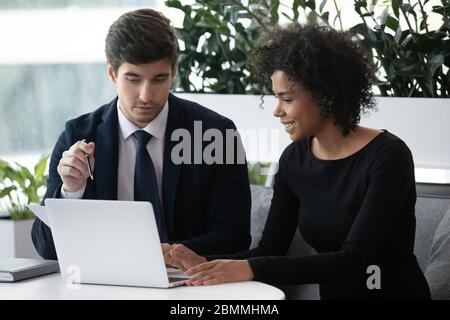 African businesswoman Caucasian businessman discussing project using laptop Stock Photo