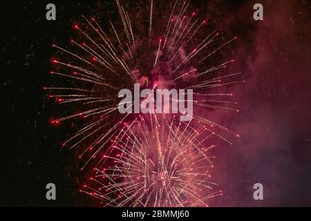 Red firework with smoke over the black sky. Low key exposure. Stock Photo