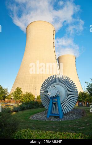 Two tall cooling towers of a nuclear power station with an old turbine as foreground. Stock Photo