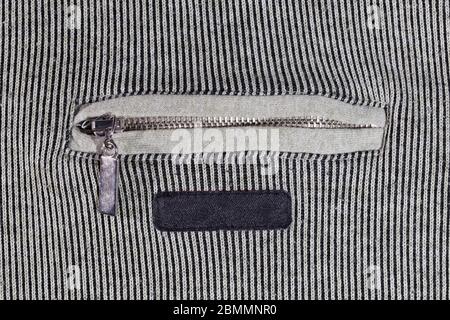 abstract vertical striped texture of flat fabric surface with zip locking chest pocket, and black blank label Stock Photo