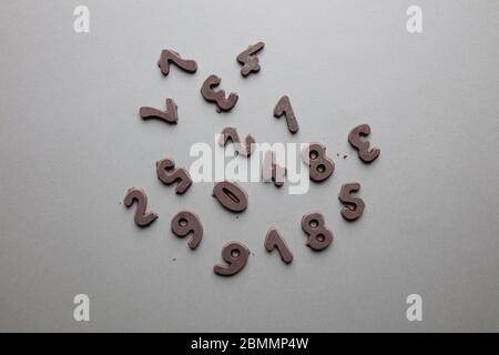 an artsy studio shot of mixed chocolate numbers against a grey background Stock Photo