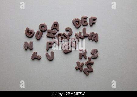 an artsy studio shot of mixed chocolate letters against a grey background Stock Photo