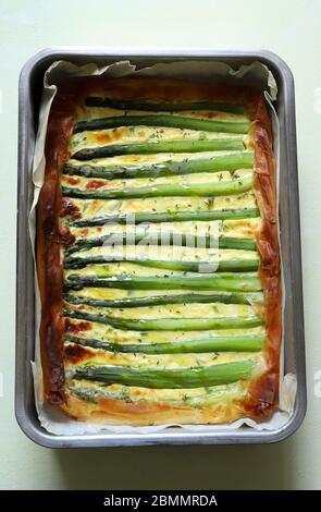 Quiche with asparagus on a tray on white background. Homemade food concept. Top view. Stock Photo