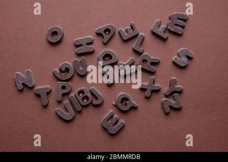 an artsy studio shot of chocolate letters against a brown background Stock Photo
