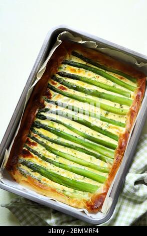 Quiche with asparagus on a tray on white background. Homemade food concept. Top view. Stock Photo